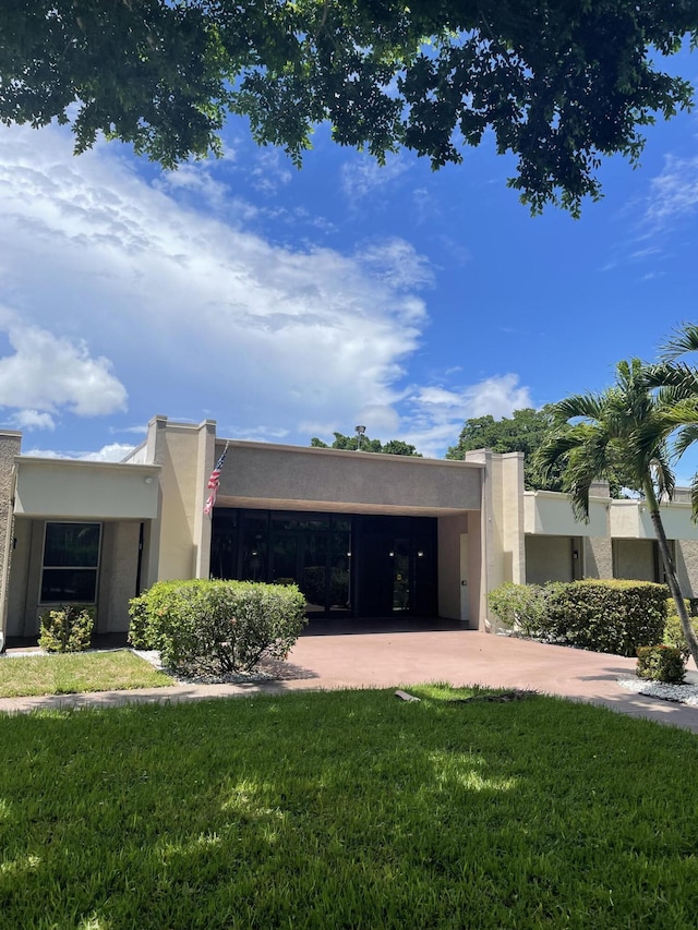 pueblo-style home with stucco siding, concrete driveway, a garage, and a front lawn