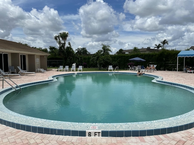 community pool with a patio and fence