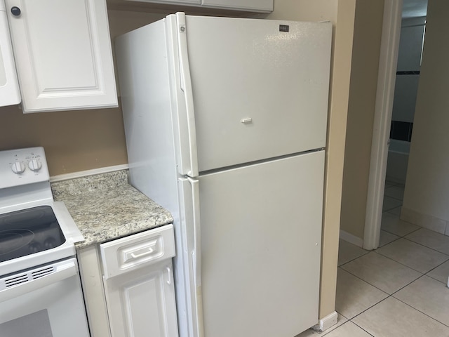 kitchen with white appliances, light tile patterned flooring, and white cabinetry