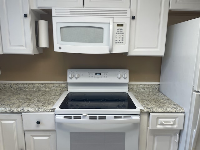 kitchen with white appliances, white cabinets, and light countertops