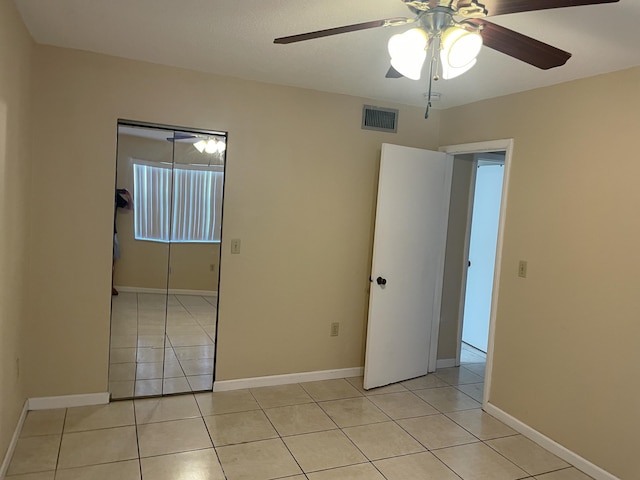 empty room featuring light tile patterned floors, ceiling fan, and baseboards