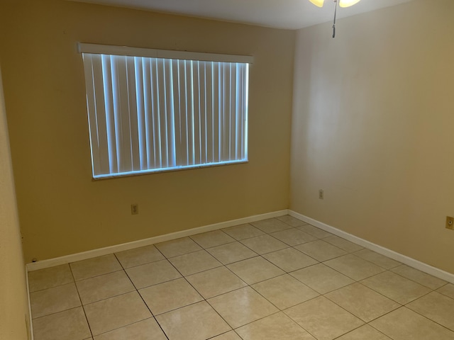 unfurnished room with light tile patterned floors, baseboards, and ceiling fan