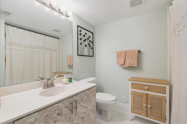 bathroom featuring toilet, tile patterned flooring, vanity, and a textured ceiling