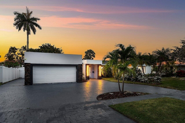 2611 NE 49th St, Lighthouse Point, FL 33064 - view of front facade with curved driveway, an attached garage, stucco siding, and stone siding
