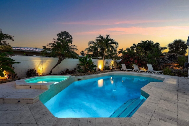 2611 NE 49th St, Lighthouse Point, FL 33064 - pool at dusk with a patio area, a fenced backyard, and a pool with connected hot tub