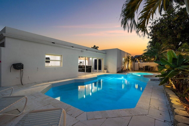 2611 NE 49th St, Lighthouse Point, FL 33064 - pool at dusk with a patio area, a pool with connected hot tub, and french doors