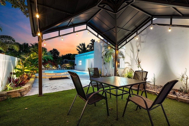 2611 NE 49th St, Lighthouse Point, FL 33064 - patio terrace at dusk featuring a lawn, a patio area, and an outdoor pool