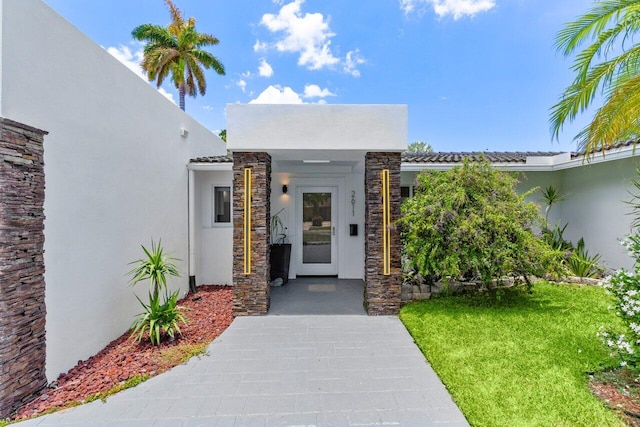 2611 NE 49th St, Lighthouse Point, FL 33064 - doorway to property with stucco siding, stone siding, a lawn, and a tile roof