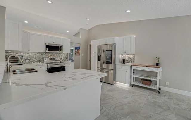 11849 59th St N, Royal Palm Beach, FL 33411 - kitchen featuring appliances with stainless steel finishes, a sink, backsplash, light stone countertops, and lofted ceiling