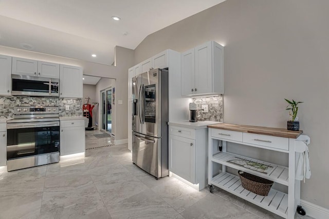 11849 59th St N, Royal Palm Beach, FL 33411 - kitchen with appliances with stainless steel finishes, decorative backsplash, lofted ceiling, baseboards, and white cabinets