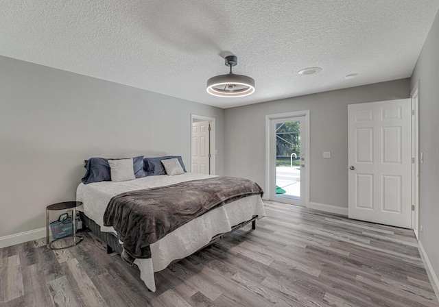 11849 59th St N, Royal Palm Beach, FL 33411 - bedroom with wood finished floors, baseboards, a textured ceiling, and access to outside