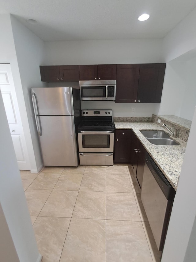 4964 Palmbrooke Cir, West Palm Beach, FL 33417 - kitchen with appliances with stainless steel finishes, a sink, dark brown cabinetry, light stone counters, and light tile patterned flooring