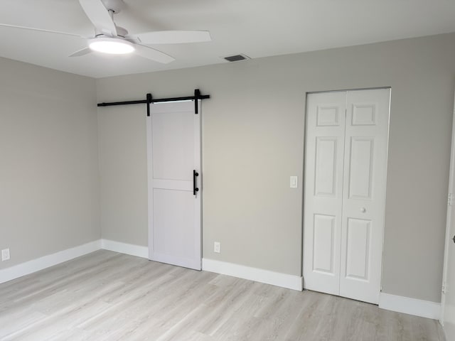 14814 Wildflower Ln, Delray Beach, FL 33446 - unfurnished bedroom with wood finished floors, a barn door, a closet, ceiling fan, and baseboards