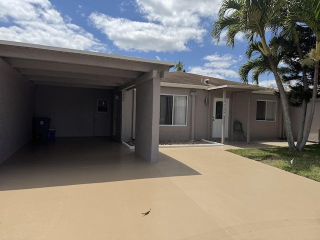 14814 Wildflower Ln, Delray Beach, FL 33446 - rear view of property with stucco siding, concrete driveway, and a carport