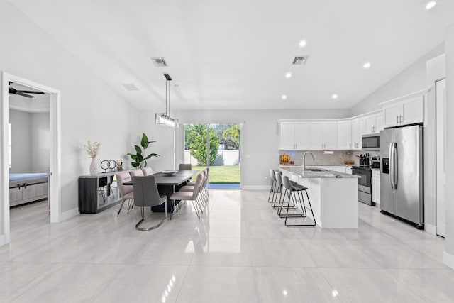 12111 Sugar Pine Trl, Wellington, FL 33414 - kitchen with stainless steel appliances, vaulted ceiling, a sink, a breakfast bar, and a kitchen island with sink