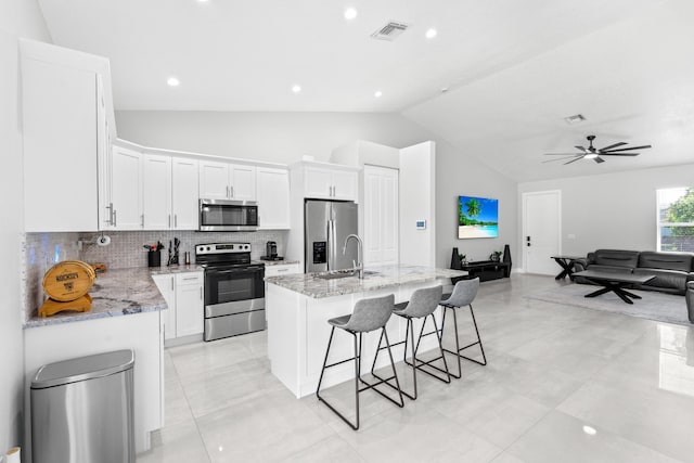 12111 Sugar Pine Trl, Wellington, FL 33414 - kitchen with appliances with stainless steel finishes, lofted ceiling, an island with sink, backsplash, and open floor plan