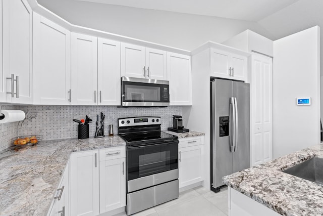 12111 Sugar Pine Trl, Wellington, FL 33414 - kitchen with appliances with stainless steel finishes, white cabinets, backsplash, light stone counters, and lofted ceiling