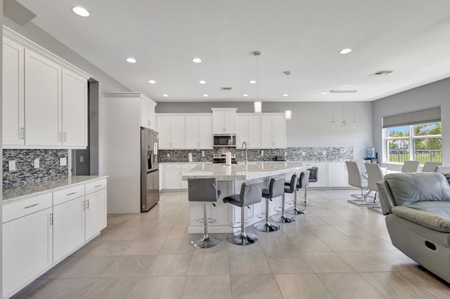 5968 Jasmine Ln, Westlake, FL 33470 - kitchen featuring stainless steel appliances, open floor plan, backsplash, a breakfast bar, and recessed lighting