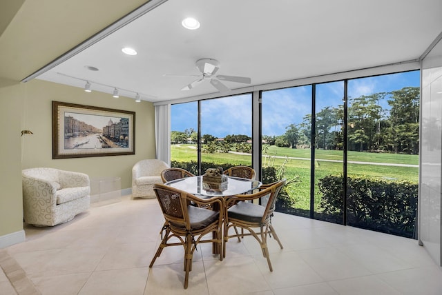 dining room featuring a wall of windows, rail lighting, a ceiling fan, baseboards, and light tile patterned floors