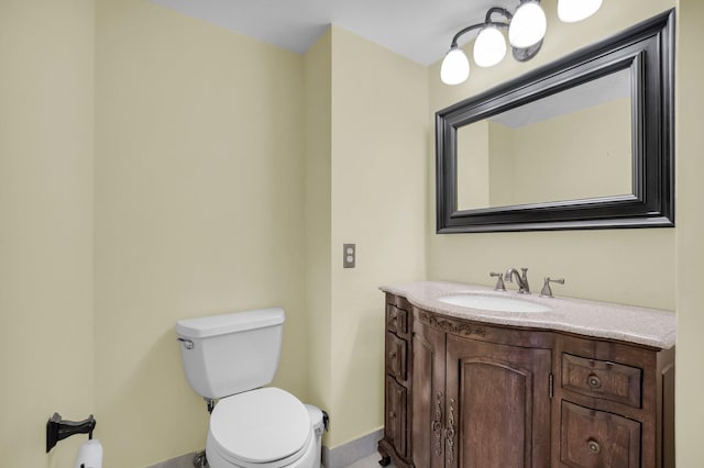 half bathroom featuring toilet, baseboards, and vanity