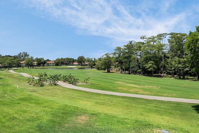 view of home's community with golf course view, a lawn, and view of scattered trees