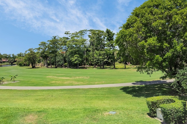 surrounding community featuring golf course view, a yard, and view of scattered trees