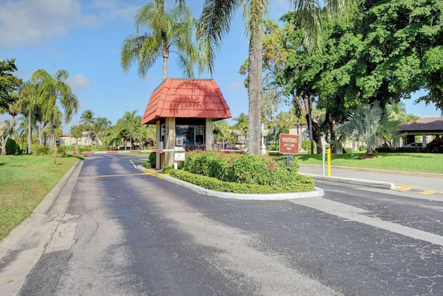 view of asphalt road with curbs and a gated entry