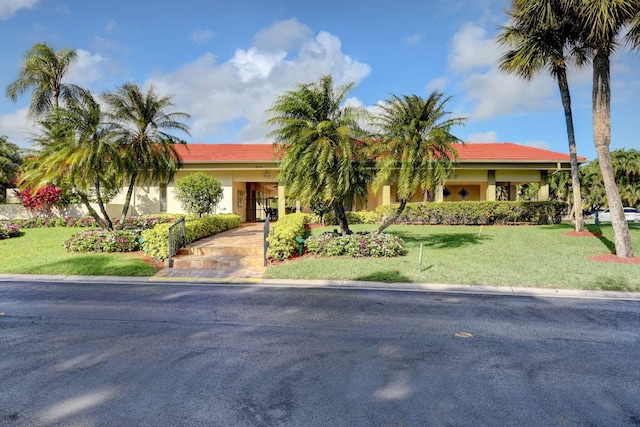view of front facade featuring stucco siding, a tile roof, and a front yard