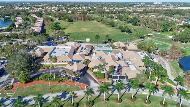 aerial view of property and surrounding area featuring a golf course, nearby suburban area, and a large body of water