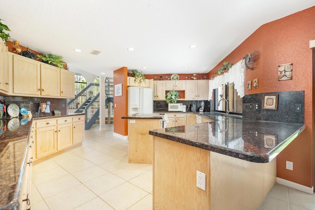 kitchen featuring white appliances, a sink, light tile patterned flooring, decorative backsplash, and a peninsula