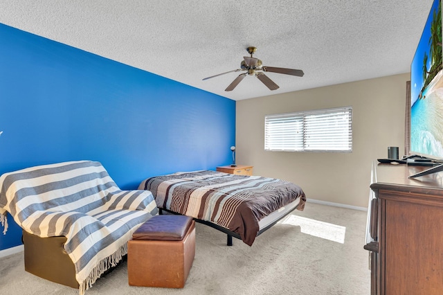bedroom featuring baseboards, light carpet, a textured ceiling, and a ceiling fan