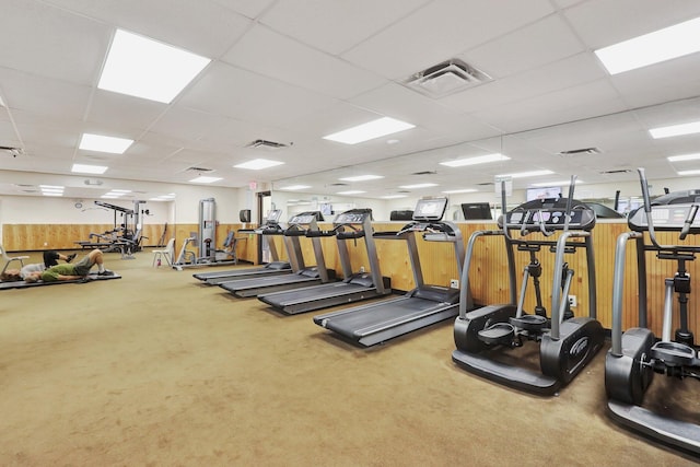 workout area with carpet, wood walls, and a paneled ceiling