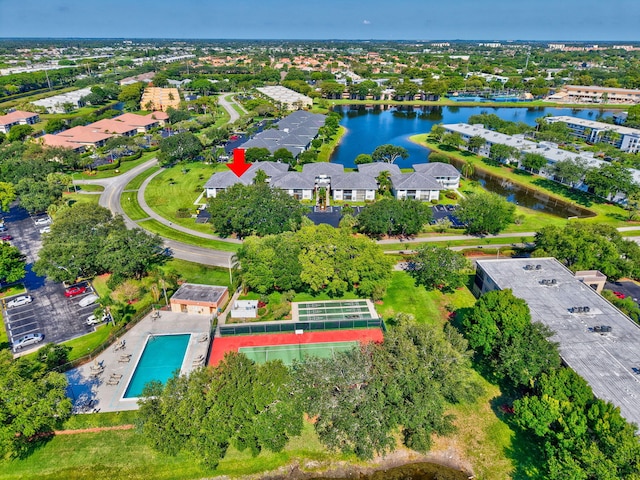 aerial view of property and surrounding area with a nearby body of water and a pool area