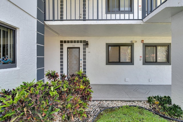 entrance to property featuring stucco siding and a balcony