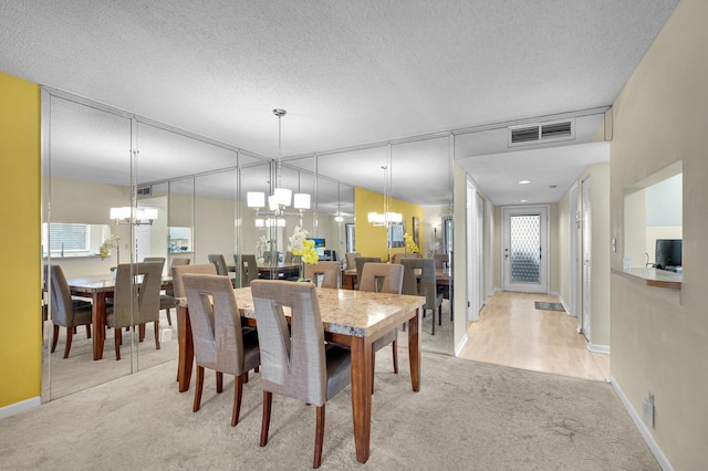 carpeted dining space with a chandelier, baseboards, and a textured ceiling