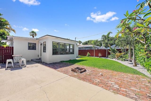 1613 N J Ter, Lake Worth Beach, FL 33460 - rear view of property featuring stucco siding, a patio area, and an outdoor fire pit