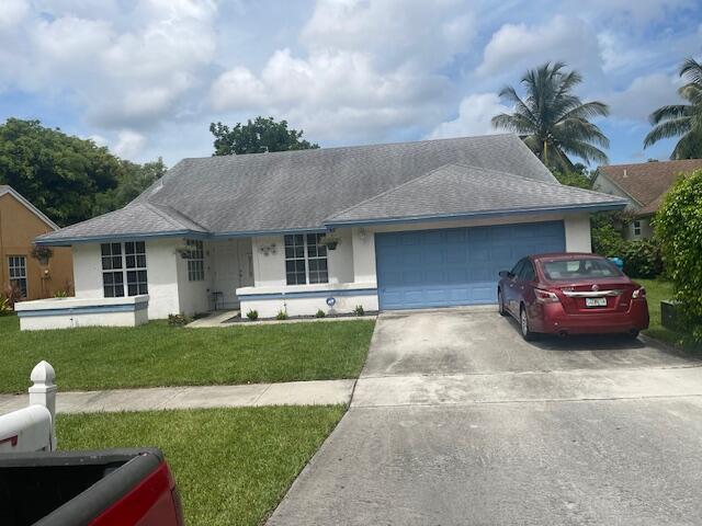 single story home featuring an attached garage, stucco siding, concrete driveway, and a front lawn