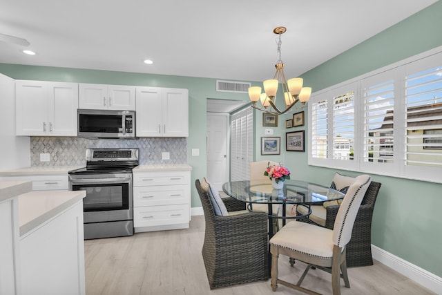 79 Saxony B B, Delray Beach, FL 33446 - kitchen featuring appliances with stainless steel finishes, a chandelier, light countertops, tasteful backsplash, and recessed lighting