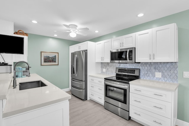 79 Saxony B B, Delray Beach, FL 33446 - kitchen with stainless steel appliances, a sink, decorative backsplash, white cabinets, and light countertops