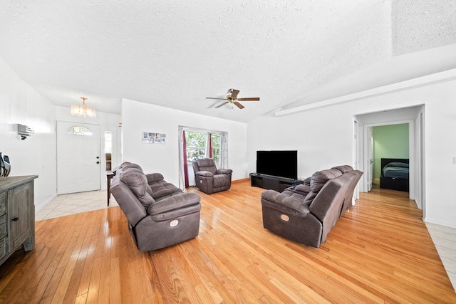 5910 NW Bayou Ct, Port Saint Lucie, FL 34986 - living area featuring a textured ceiling, vaulted ceiling, light wood-style floors, a ceiling fan, and a chandelier