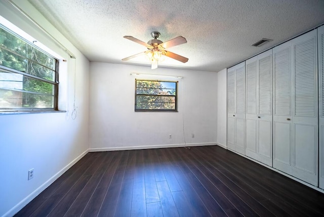 4424 Regency Dr, Lake Worth, FL 33461 - unfurnished bedroom featuring multiple windows, baseboards, a textured ceiling, dark wood-type flooring, and ceiling fan