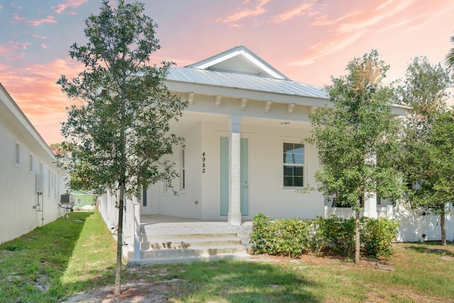 4982 SE Railway Ave, Stuart, FL 34997 - view of front of home with covered porch, stucco siding, a lawn, and metal roof