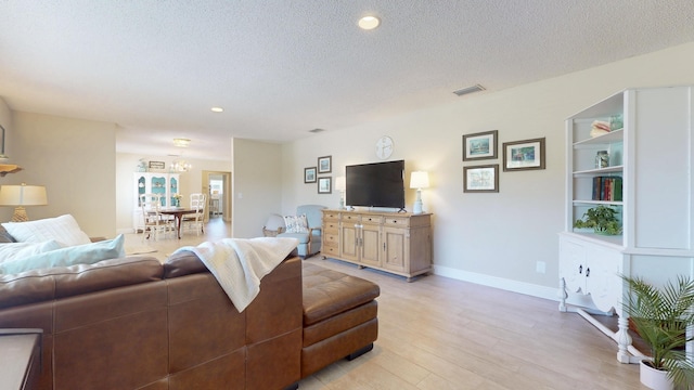 living room featuring light wood finished floors, a textured ceiling, baseboards, and recessed lighting