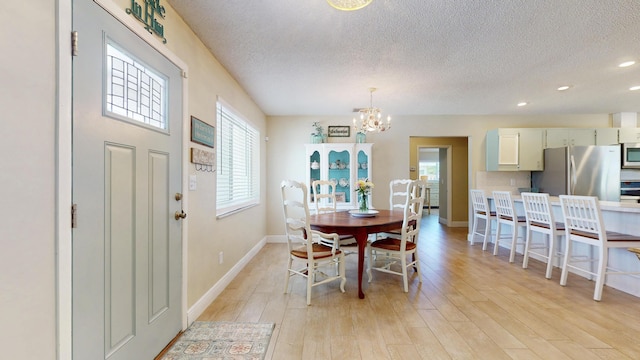 dining space with a textured ceiling, a chandelier, light wood-style floors, baseboards, and recessed lighting