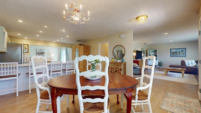 dining room with light wood-style floors, recessed lighting, a textured ceiling, and a chandelier