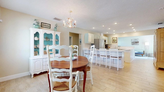 dining space with a textured ceiling, recessed lighting, a chandelier, light wood-style flooring, and baseboards