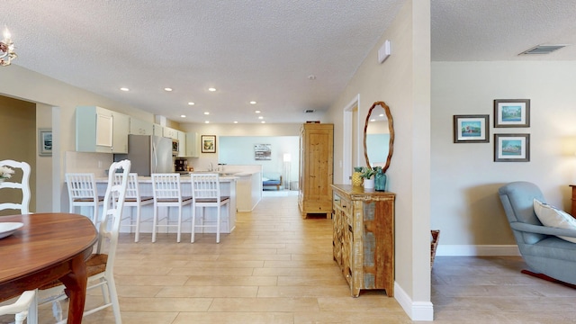 kitchen with stainless steel appliances, a textured ceiling, a peninsula, light wood-type flooring, and light countertops
