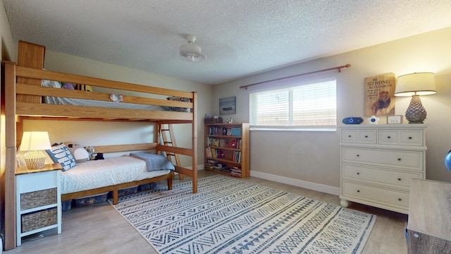 bedroom featuring a textured ceiling, wood finished floors, and baseboards
