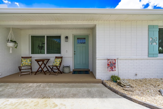 property entrance featuring covered porch and brick siding