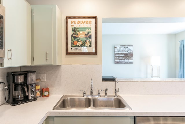 kitchen with a sink, stainless steel dishwasher, light countertops, and tasteful backsplash
